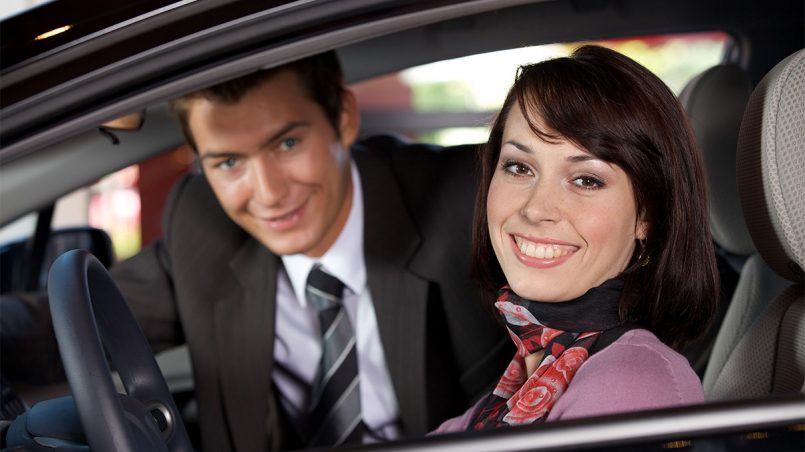 Couples sitting in a used car at showroom